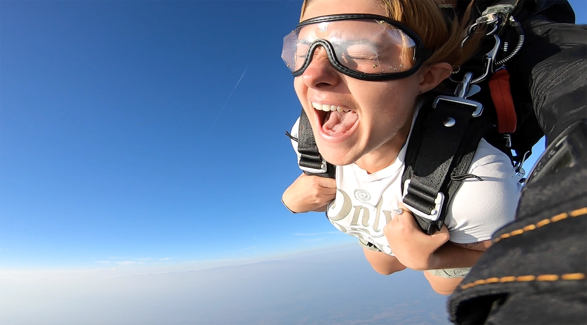 Sourire en chute libre sur fond de ciel bleu pendant un saut en parachute tandem